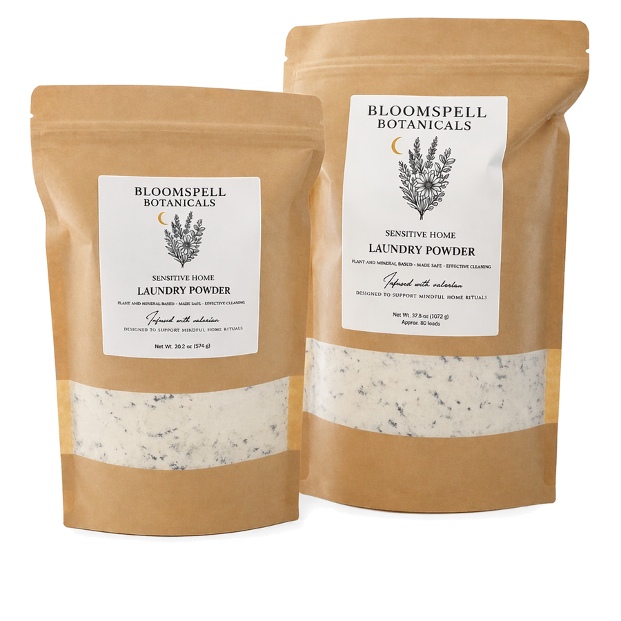Two kraft-paper pouches of Bloomspell Botanicals Laundry Powder — Sensitive Home, large and small sizes.
